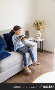 Young girl is using her laptop on the living room sofa