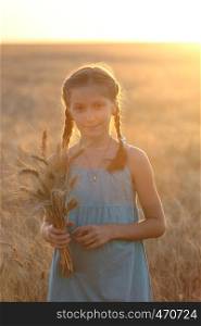 young girl joys on the wheat field at the sunset time