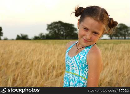 young girl joys on the wheat field with blue cloudy sky at the background.