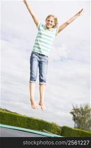 Young girl jumping on trampoline smiling