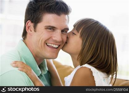 Young girl kissing smiling man in living room