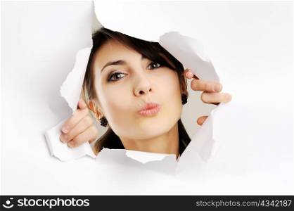 Young girl kissing through hole in white paper