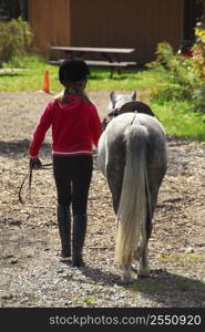 Young girl leading her pony back to the stable