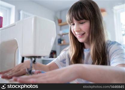 Young Girl Learning How To Use Sewing Machine At Home