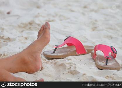 Young girl legs and flip-flop on the sand beach in summer