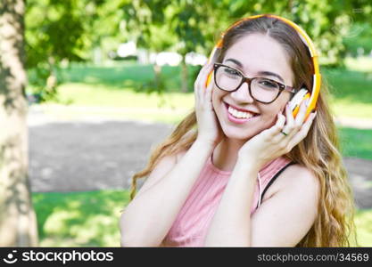 young girl listen music with headphone in the park