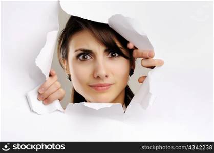 Young girl looking through hole in white paper