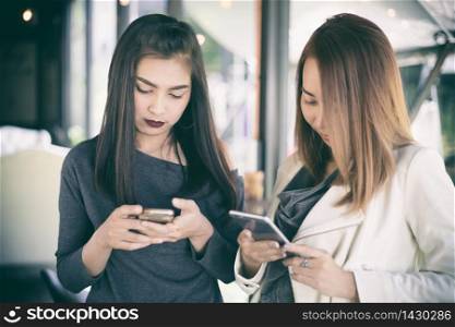 Young girl looking to her friend&rsquo;s phone and feeling exciting and smiling while sitting in living room at office