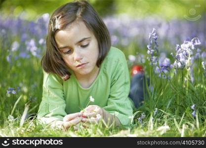 young girl lying in a wood full of bluebells