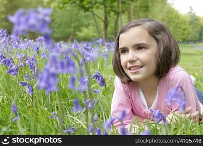 young girl lying in a wood full of bluebells