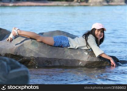 Young girl lying on a rock