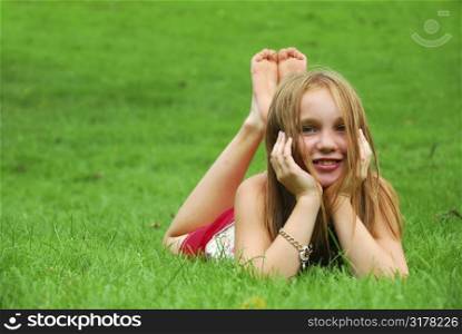 Young girl lying on green grass in the summer