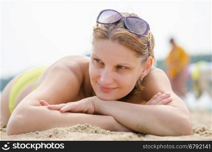 Young girl lying on sandy beach and looking to the side
