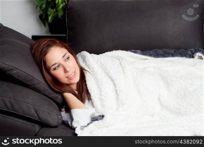Young girl lying on the couch covered with a blanket