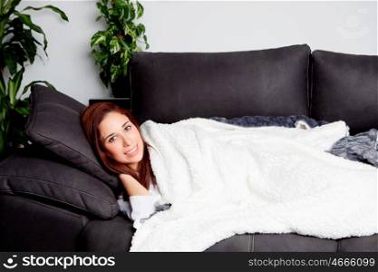 Young girl lying on the couch covered with a blanket
