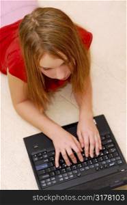 Young girl lying on the floor with portable computer