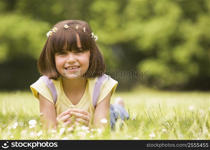 Young girl lying outdoors with flowers smiling