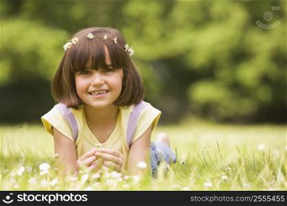 Young girl lying outdoors with flowers smiling