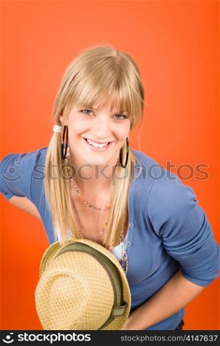 Young girl make a curtsy hold hat on orange background
