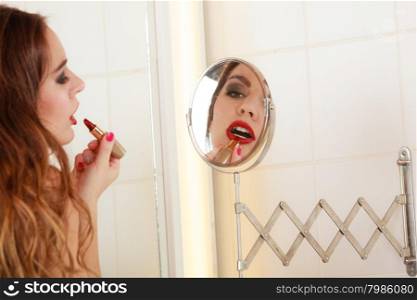 Young girl making makeup. Pretty girl making makeup in bathroom. Woman take care about look. Looking into a mirror.