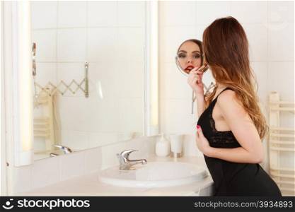 Young girl making makeup. Young girl making makeup in bathroom. Woman take care about look. Looking into a mirror.