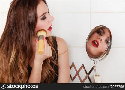 Young girl making makeup. Young girl making makeup in bathroom. Woman take care about look. Looking into a mirror.