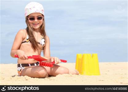 Young girl making sandcastles on a beach