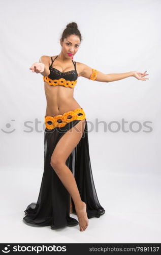 Young girl mulatto dancing in a long black candid open dress, is isolated on a light background