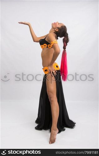 Young girl mulatto dancing in a long black candid open dress, is isolated on a light background