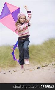 Young girl on beach with kite smiling