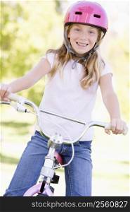 Young girl on bicycle outdoors smiling