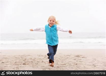 Young Girl On Holiday Running Along Winter Beach