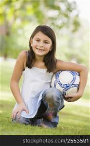 Young girl outdoors at park holding ball and smiling (selective focus)