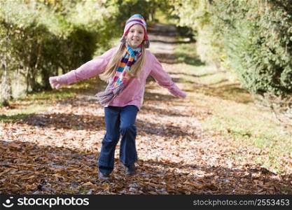 Young girl outdoors at park running on path smiling (selective focus)
