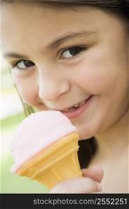 Young girl outdoors eating ice cream and smiling (selective focus)