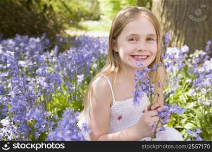 Young girl outdoors holding flowers smiling