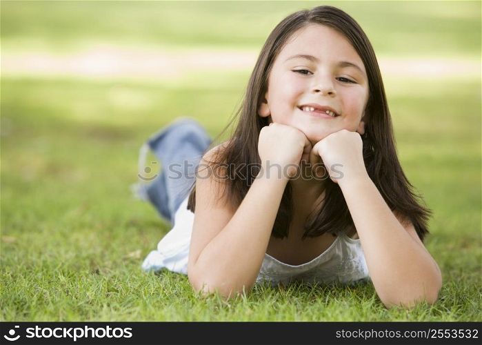 Young girl outdoors lying in grass and smiling (selective focus)