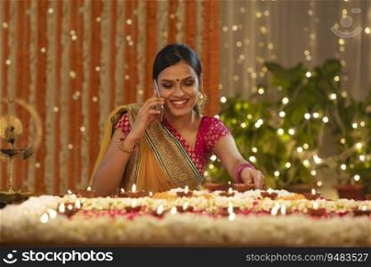 Young girl placing  diwali diyas while being engaged on a call