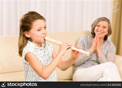Young girl play flute with proud grandmother happy teacher clapping