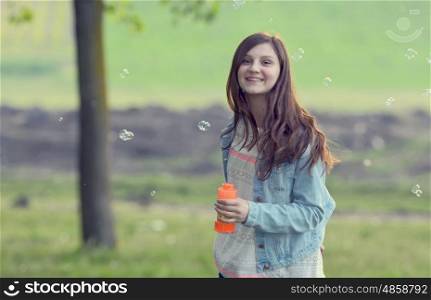 Young girl play with soap-bubbles in forest