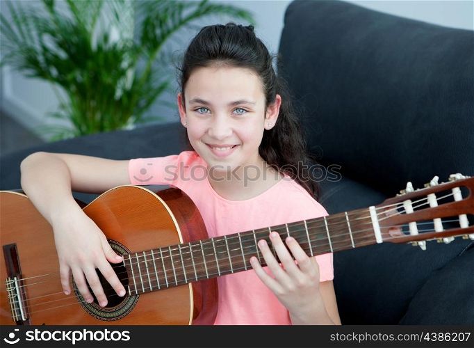 Young girl playing a guitar on the sofa at home