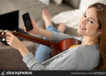 young girl playing guitar and recording music in computer
