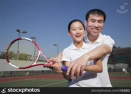 Young girl playing tennis with her coach