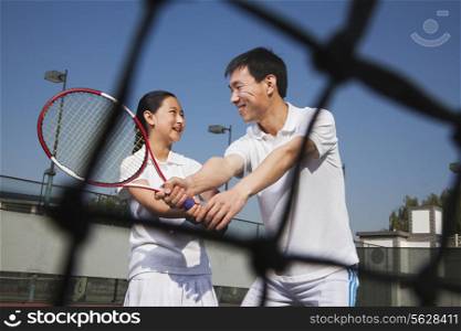 Young girl playing tennis with her coach