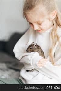 Young girl playing with cute chilean degu squirrel.  Cute pet sitting on kid&rsquo;s hand