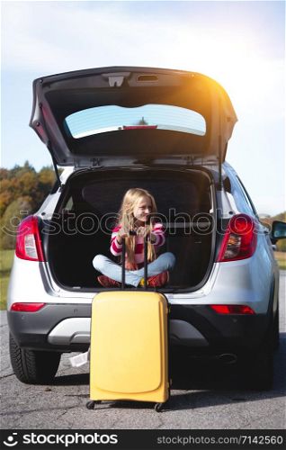 young girl portrait at the car trunk. Roadtrip