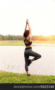 young girl practicing yoga exercises outdoor in park. calmness and relax concept, woman happiness