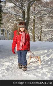 Young Girl Pulling Sledge Through Snowy Landscape
