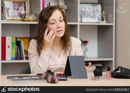Young girl puts makeup in the office workplace