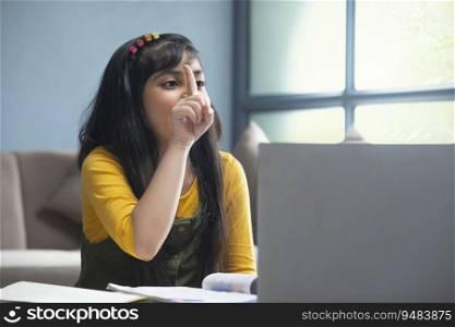Young girl raising her finger in front of the laptop to ask a question during her online class